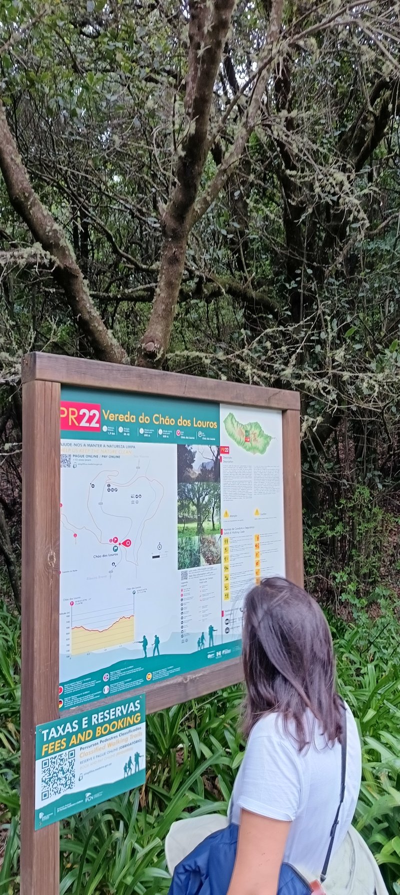 Hiker reading the PR 22 trail information board and map at Chão dos Louros